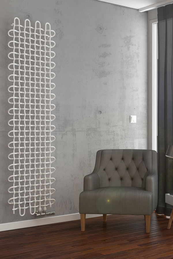Designheizkörper PLC V weiß arrangiert Beton Wand neben Sessel