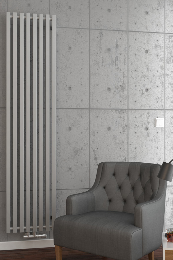 Designheizkörper Triga V frontal in weiß Beton Wand und Sessel